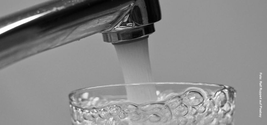 Aus einem Wasserhahn fließt Wasser in ein Trinkglas