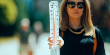 Eine Frau zeigt ein Thermometer